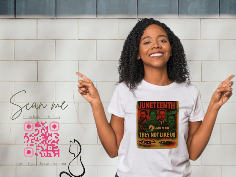 May include: White t-shirt featuring a graphic with the text "Juneteenth" and "They Not Like Us". The graphic includes images of four men. A QR code and the text "Scan me" are also visible.