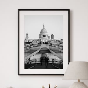Può includere: Una fotografia in bianco e nero di un ponte a Londra con la Cattedrale di San Paolo sullo sfondo.
