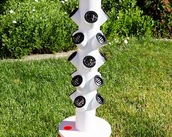 May include: A white plastic vertical garden tower with black mesh pots. The tower is sitting on top of an orange bucket with the Home Depot logo.