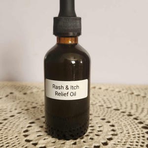 May include: A brown glass bottle with a black dropper top. The bottle is labelled "Rash & Itch Relief Oil".