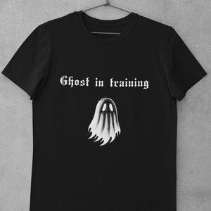 May include: Black t-shirt with a white ghost graphic and the text "Ghost in training" in a gothic font.
