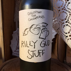 May include: A black wine bottle with a white label. The label features a cartoon illustration of a creature with a large smile holding a mug of beer. The text on the label reads "Gullettfire The Grogmaster's Rilly Gud Stuff".