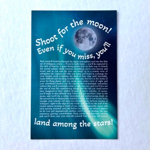 May include: A blue and purple galaxy-themed print with a white moon and text that reads "Shoot for the moon! Even if you miss, you'll land among the stars!"