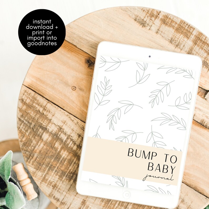 Op de afbeelding: Een witte tablet met een digitale journal cover. De cover heeft een licht beige achtergrond met de tekst "BUMP TO BABY journal" in zwart. De achtergrond is versierd met een patroon van grijze bladeren.