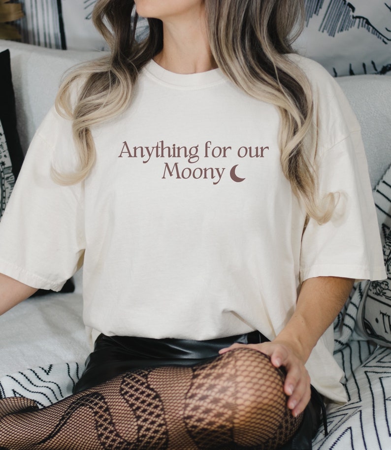 Może przedstawiać: Biały t-shirt z nadrukiem "Anything for our Moony" i p&oacute;łksiężycem w kolorze brązowym.