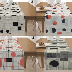 Könnte beinhalten: Vier Tischläufer mit geometrischen Mustern, die auf einem Holztisch präsentiert werden. Jeder Läufer hat ein anderes Design mit Formen wie Kreisen, Quadraten und Linien in Schwarz, Rot und Grau. Auf dem Tisch stehen Teller mit Kuchen.