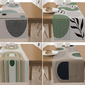 Könnte beinhalten: Ein Set aus vier Tischläufern mit abstrakten geometrischen Designs. Jeder Läufer hat ein anderes Muster in neutralen Tönen mit Akzenten in Schwarz, Grün und Braun. Die Läufer werden auf einem Holztisch präsentiert.