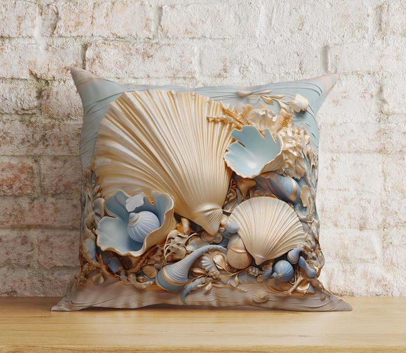 Puede incluir: Un coj&iacute;n cuadrado con un dise&ntilde;o detallado en relieve de varias conchas marinas en tonos crema, dorado y azul p&aacute;lido. La composici&oacute;n central incluye conchas grandes en forma de abanico, conchas en espiral m&aacute;s peque&ntilde;as y texturas de coral.