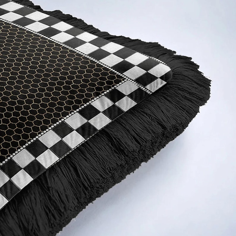 Puede incluir: Coj&iacute;n decorativo con un patr&oacute;n en blanco y negro y flecos. El coj&iacute;n presenta un dise&ntilde;o geom&eacute;trico con un patr&oacute;n de panal y un borde a cuadros. Los flecos negros a&ntilde;aden textura al dise&ntilde;o.