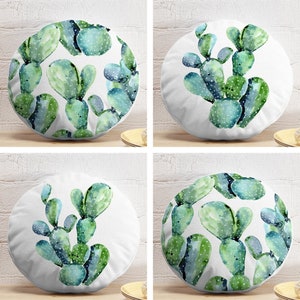 Op de afbeelding: Vier ronde kussens met een aquarel cactusontwerp in groen en blauw op een witte achtergrond. De cactussen hebben een gedetailleerd, handgeschilderd uiterlijk, met kleine witte stippen. De kussens zijn vierkant gerangschikt.