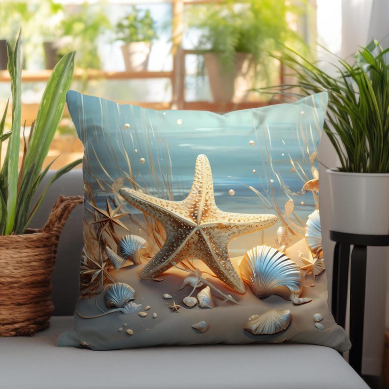 Puede incluir: Un coj&iacute;n cuadrado con una escena costera que presenta una estrella de mar dorada central sobre un suelo arenoso. El dise&ntilde;o incluye varias conchas marinas, peque&ntilde;as piedras dispersas y hierbas altas sobre un fondo azul suave.