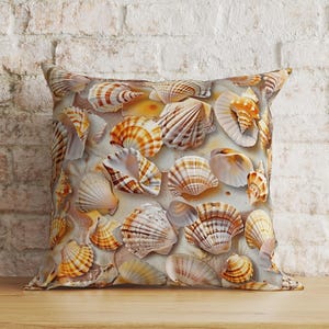 Puede incluir: Un coj&iacute;n cuadrado con un patr&oacute;n detallado y repetitivo de varias conchas marinas en tonos bronceado, marr&oacute;n, naranja y blanco. El dise&ntilde;o muestra una colecci&oacute;n de conchas de abanico, caracolas y conchas espirales sobre un fondo arenoso.