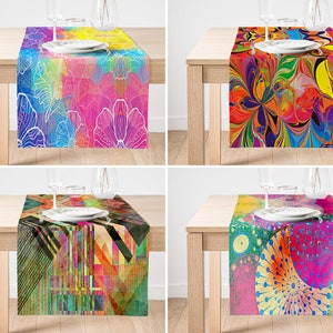 Puede incluir: Cuatro caminos de mesa coloridos con diferentes diseños abstractos. Cada camino de mesa presenta un patrón único con colores vibrantes, incluyendo rosa, azul, verde, amarillo, naranja y rojo. Los caminos de mesa se muestran en mesas de madera con vasos y platos.