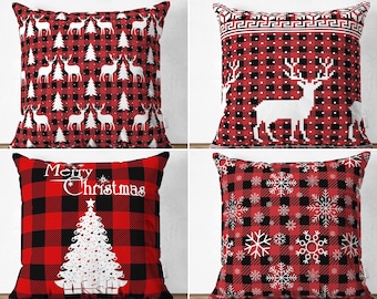 Puede incluir: Un conjunto de cuatro cojines cuadrados con un patrón de cuadros rojos y negros. Los diseños incluyen siluetas blancas de renos y pinos, un reno grande pixelado, un árbol de Navidad con el texto Merry Christmas y copos de nieve.