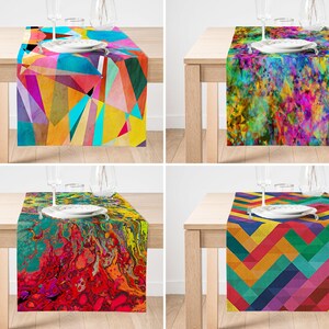 May include: Four rectangular table runners featuring distinct colourful patterns: one with geometric triangles, one with a vibrant abstract splatter design, one with a fluid marbled paint effect, and one with a multi-coloured chevron pattern.