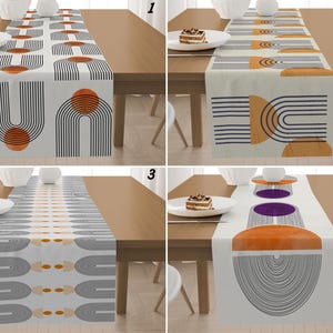 Op de afbeelding: Vier tafellopers met geometrische ontwerpen worden getoond op houten tafels. De lopers hebben abstracte patronen met bogen, lijnen en cirkels in kleuren als oranje, grijs en paars. Elke loper ligt op een tafel met een bord en een kleine cake.