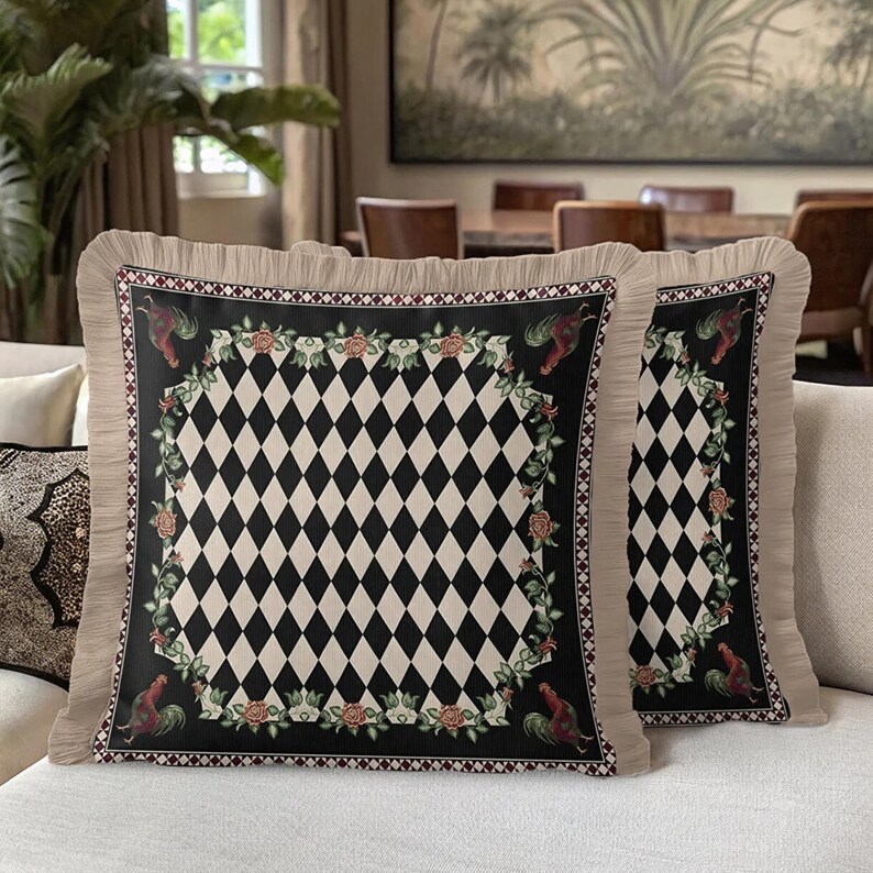Puede incluir: Dos cojines cuadrados decorativos con un patr&oacute;n central de diamantes en blanco y negro, enmarcados por un borde negro con acentos de gallos y flores. Los cojines tienen un borde con volantes beige, agregando un toque de elegancia.