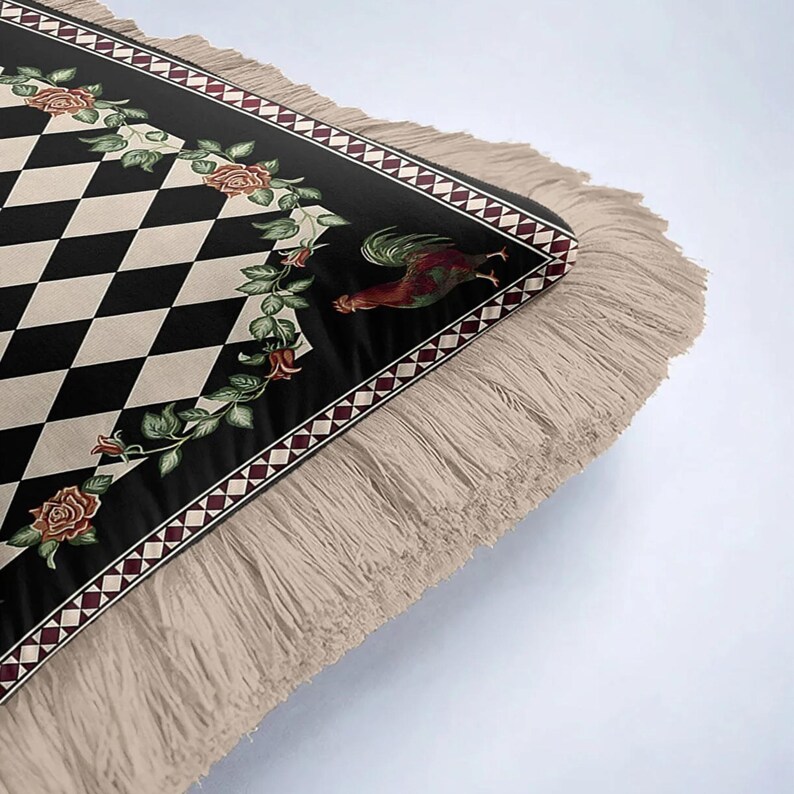 Puede incluir: Una alfombra decorativa con un patr&oacute;n de diamantes en negro y crema. El borde de la alfombra es negro con un dise&ntilde;o floral y un gallo. La alfombra tiene flecos beige.