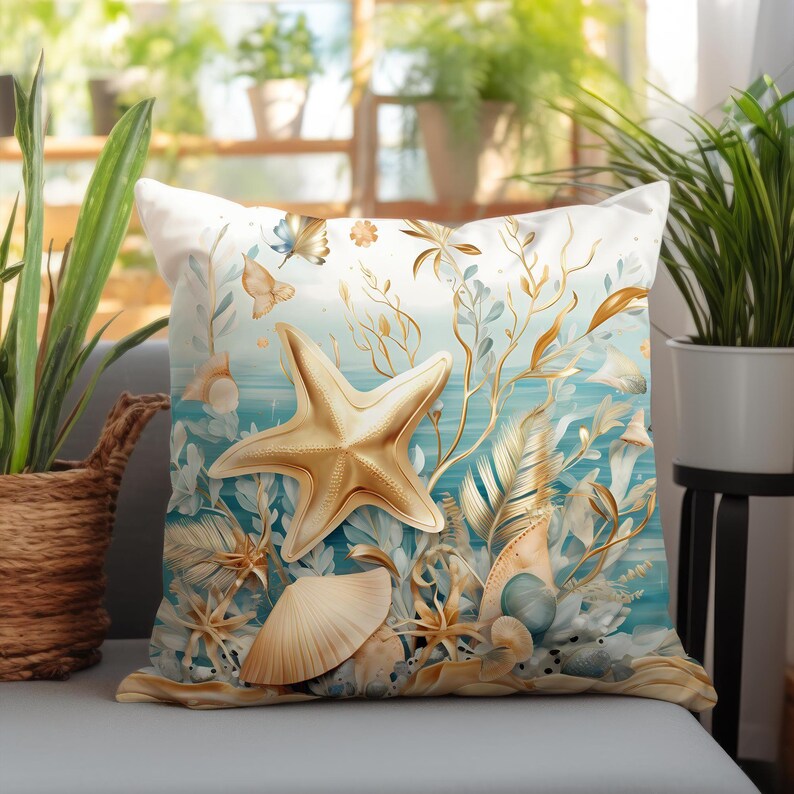 Puede incluir: Un coj&iacute;n cuadrado con un dise&ntilde;o estampado de una gran estrella de mar dorada, varias conchas marinas y delicados patrones de algas doradas sobre un fondo degradado en tonos blanco y azul claro de agua oce&aacute;nica.