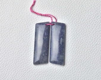 May include: Two rectangular blue-grey gemstone beads with a pink thread attached.