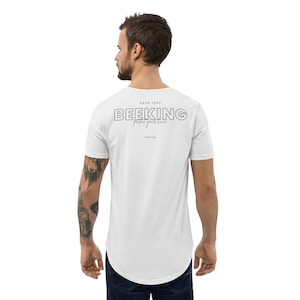 以下が含まれることがあります： 黒のグラフィックがプリントされた白い長袖Tシャツ。グラフィックには「BEEKING protect your hive」と書いてあり、その上に「DAD-TUFF」という文字が書かれている。