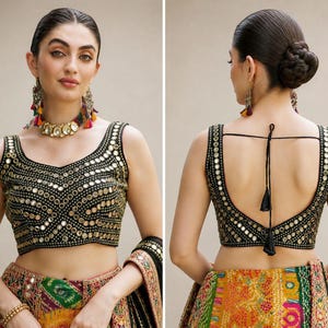 May include: A black sleeveless blouse featuring intricate gold-toned mirror work embroidery in a geometric pattern. The front has a scoop neckline, while the back features a deep scoop design with thin black tie-up strings and decorative tassels.