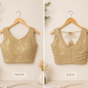 May include: A sleeveless gold blouse featuring intricate embroidery and small circular mirrors throughout the fabric. The front displays a V-neckline, while the back features a deep V-neck with a tie-up closure and two decorative tassels.