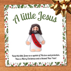 May include: A Christmas card with the text "A little Jesus" and a small figurine of Jesus. The card has a holly and berry border and a gold bow. The text reads "Keep this little Jesus as a symbol of His love and protection. Have a Merry Christmas and a blessed New Year!"