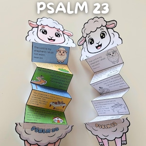 Puede incluir: Dos manualidades de papel con forma de oveja, cada una con el texto "PSALM 23" y versículos bíblicos. Las manualidades tienen un fondo blanco con ilustraciones y texto coloridos. La parte superior de cada oveja tiene una cara sonriente.