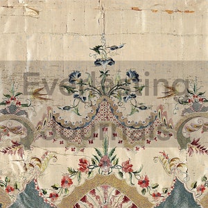 Op de afbeelding: Een vintage geborduurde stof met een bloemenpatroon. De stof heeft een centraal motief van blauwe bloemen met groene bladeren, omringd door kleinere bloemenpatronen in tinten rood, groen en geel. De stof is beige en heeft een textuur.