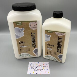 May include: Two white plastic bottles of Jesmonite AC 100, one labeled "Base" and the other labeled "Liquid". The bottles are made from recycled materials and are for use with Jesmonite resin and pigment.