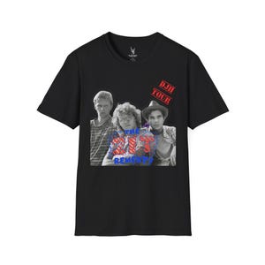 Puede incluir: Camiseta negra con una imagen en blanco y negro de tres hombres. La imagen tiene el texto "THE PIT REMEDY?" y "DJH TOUR" en rojo. La camiseta está hecha de un material suave.