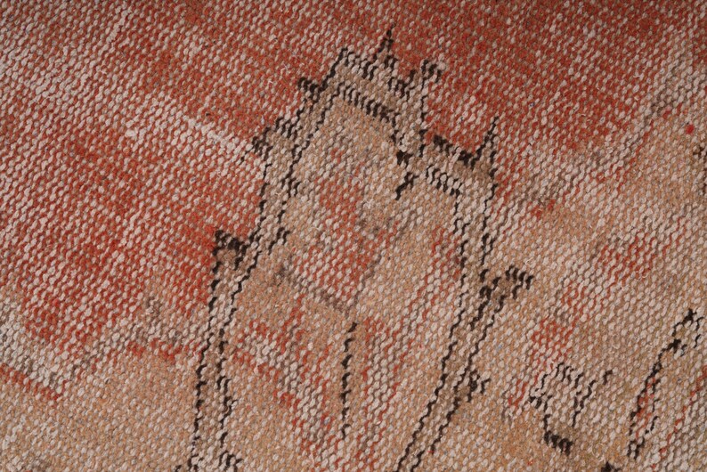 May include: Close-up of a woven rug with a geometric pattern in shades of brown, beige, and red.