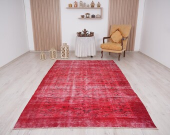 Könnte beinhalten: Ein roter Vintage-Teppich mit verblassem, abgenutztem Look. Der Teppich hat ein dezentes Muster und ist perfekt, um jedem Raum einen Hauch von Boho-Stil zu verleihen.