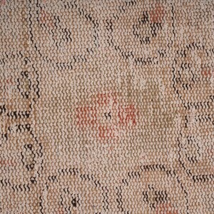May include: Close-up of a beige woven rug with a repeating pattern of black and brown lines. The rug has a faded, vintage look with hints of red and orange.