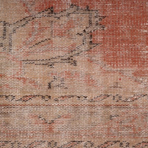 May include: Close-up of a woven rug with a faded red and beige pattern. The rug has a distressed look with a worn texture.
