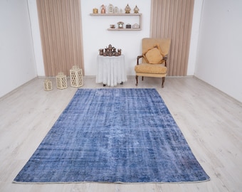 May include: A blue distressed rug with a faded appearance, laid out on a light wood floor in a room with white walls and a yellow armchair.