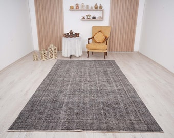 May include: A gray and white patterned rug with a distressed look. The rug is laid out on a light wood floor in a room with white walls and a wooden chair.