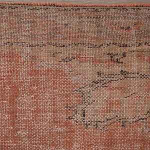May include: Close-up of a vintage rug with a faded peach and beige color scheme. The rug has a woven pattern with a geometric design.