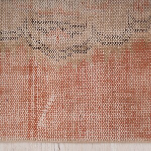 May include: Close-up of a woven rug with a textured surface. The rug has a light brown and orange color with a darker brown pattern.
