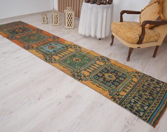 May include: A long, narrow rug with a colorful geometric pattern in shades of orange, blue, green, and yellow. The rug has a traditional, vintage look and would add a touch of bohemian style to any room.