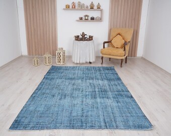May include: A blue distressed rug with a subtle pattern. The rug is laid out on a light wood floor in a room with a white chair and decorative lanterns.
