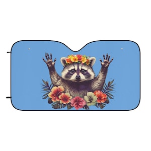 Könnte beinhalten: Blauer Autosonnenschutz mit einer Illustration eines Waschbären. Der Waschbär trägt einen Blumenkranz und hat die Arme erhoben. Helle Blumen und grüne Blätter umgeben den Waschbären vor einem hellblauen Hintergrund.