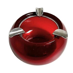 May include: A red glass ashtray with three silver metal cigarette rests.