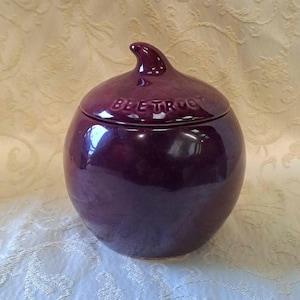 May include: A purple ceramic beetroot-shaped container with a lid. The lid has the word "BEETROOT" embossed on it.