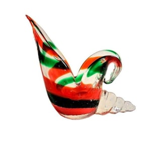 May include: A glass sculpture of a bird with red, green and black stripes. The bird is in a flying pose with its wings spread out.