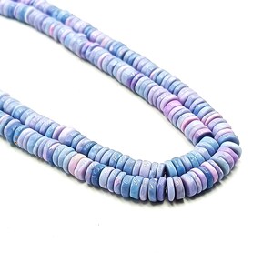 May include: A close-up of two strands of light blue and lavender gemstone beads. The beads are flat, round, and uniform in size. The background is plain white, highlighting the colors and textures of the beads. The beads are likely used for jewelry making.
