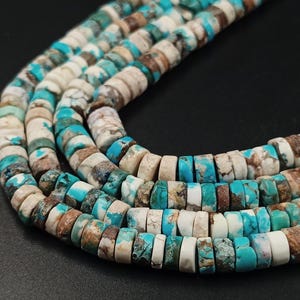 May include: Close-up of several strands of turquoise and white gemstone beads. The beads are flat, disc-shaped, and have a natural, earthy appearance. The color palette includes shades of turquoise, white, and brown, creating a unique and eye-catching design.