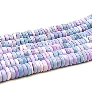 May include: Strands of pastel-colored beads in shades of lavender, light blue, and pink. The beads are flat, round, and have a slightly irregular shape. These beads are suitable for jewelry making.