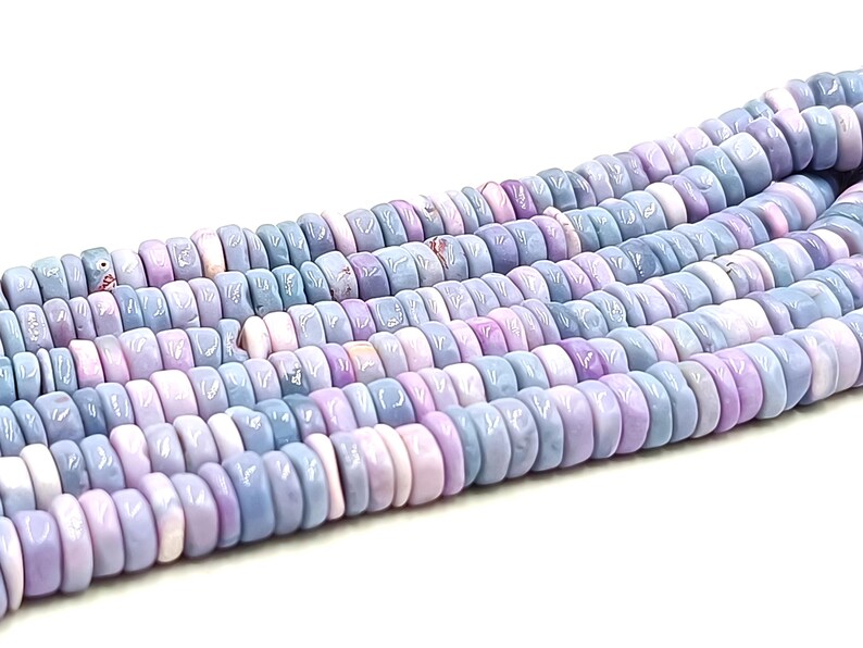 May include: Strands of pastel-colored beads in shades of lavender, light blue, and pink. The beads are flat, round, and have a slightly irregular shape. These beads are suitable for jewelry making.
